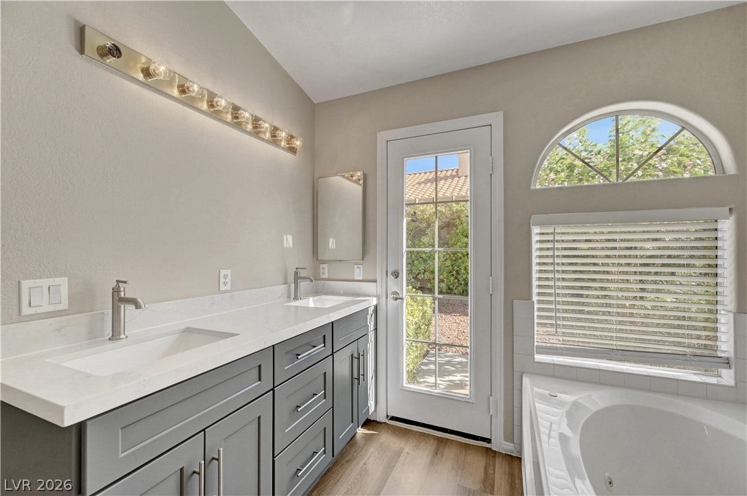 An arched window and glass door bring natural light into this updated bathroom.