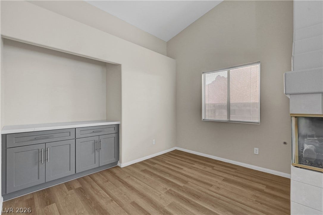 High vaulted ceilings and wood-style flooring elevate this versatile living space featuring built-in cabinetry.