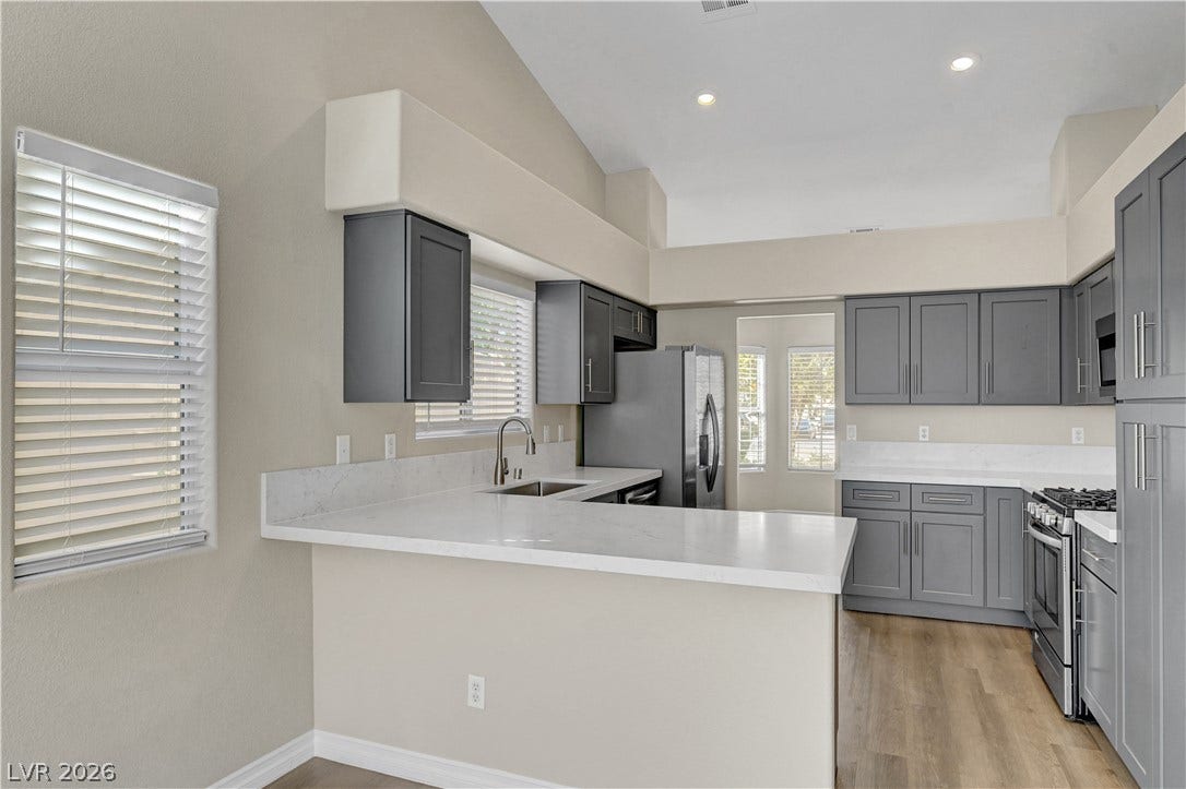 Gleaming stone countertops and modern cabinetry highlight this kitchen with vaulted ceilings and wood-style flooring.