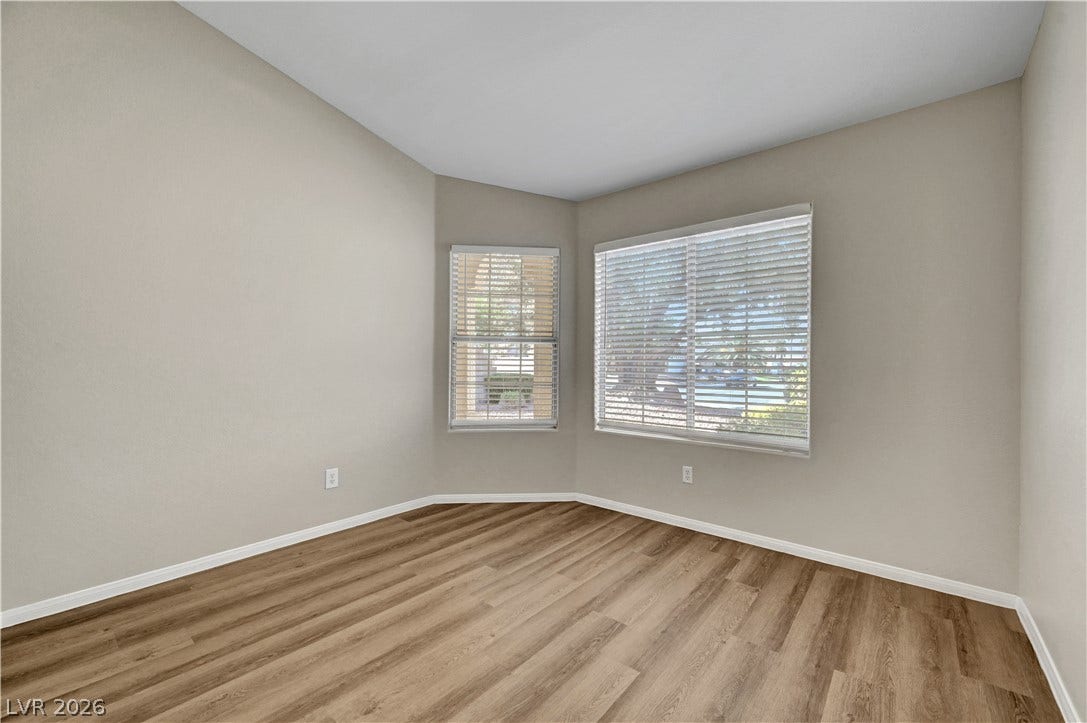 Rich wood-look flooring and dual windows create a serene, light-filled atmosphere.