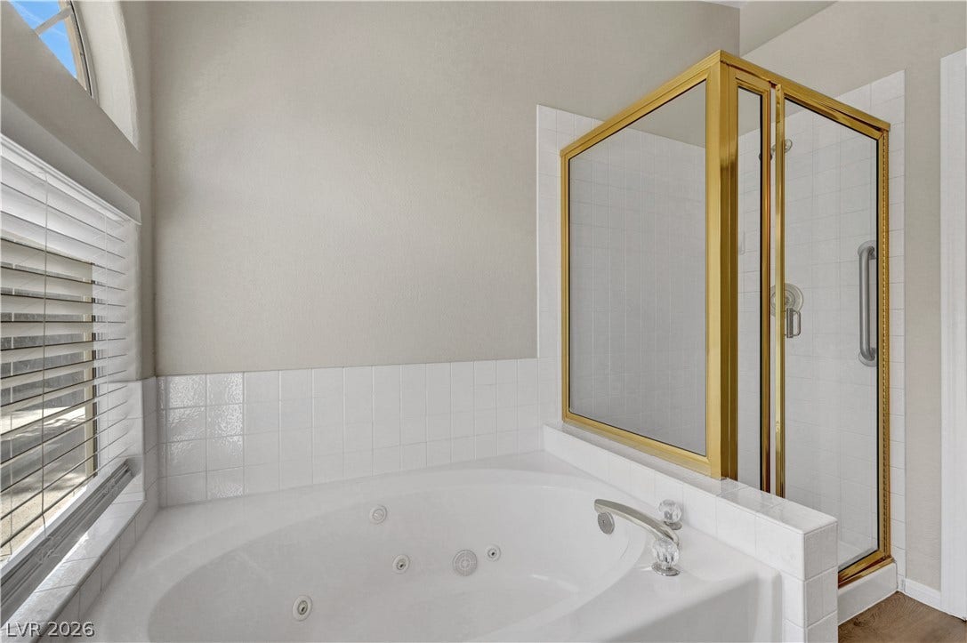 An inviting soaking tub pairs with a separate brass-trimmed walk-in shower in this master bath.