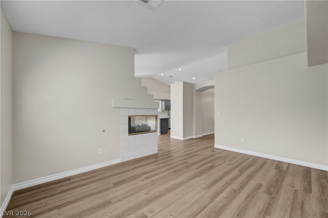 A two-sided fireplace and plank flooring define this airy living space with high ceilings.