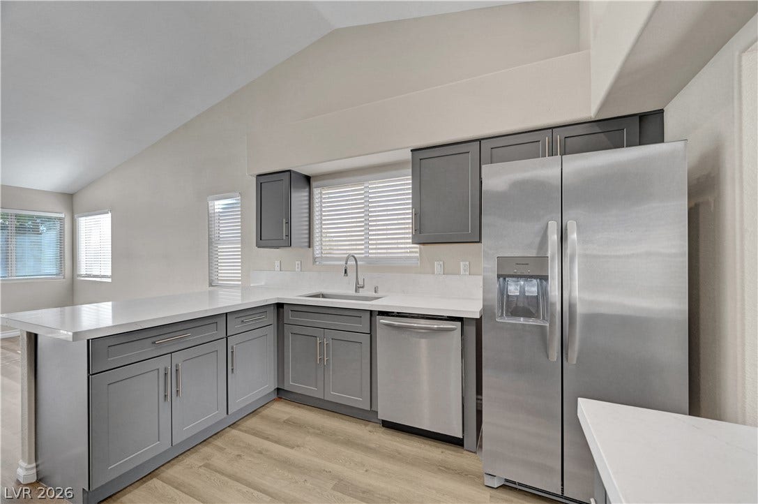 Vaulted ceilings soar over clean stone countertops and stainless steel appliances in this modern kitchen.
