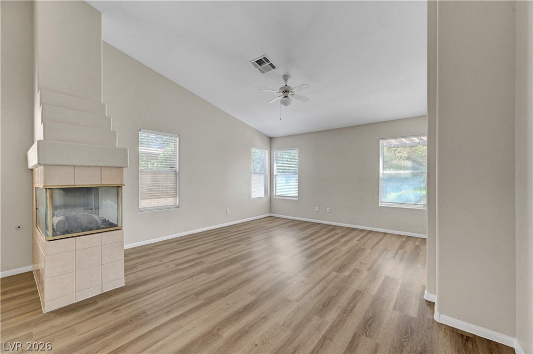 Warm wood-look flooring and a unique tiled fireplace anchor this airy, high-ceilinged living space.