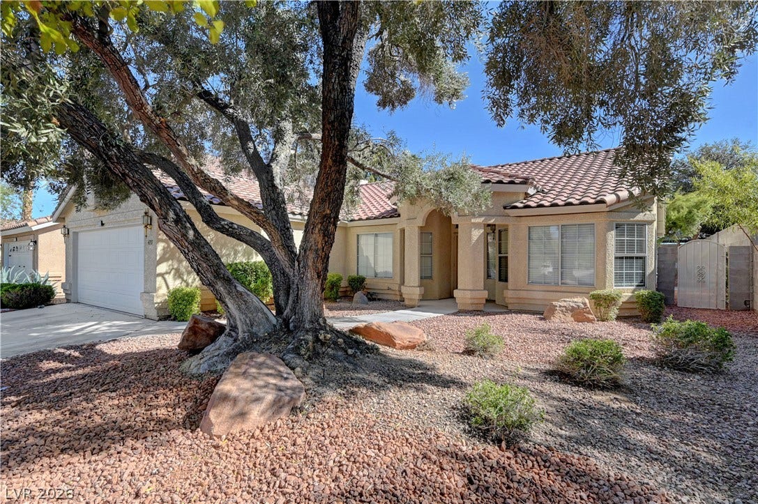 Mature trees frame this elegant stucco home with a timeless tile roof and integrated garage.