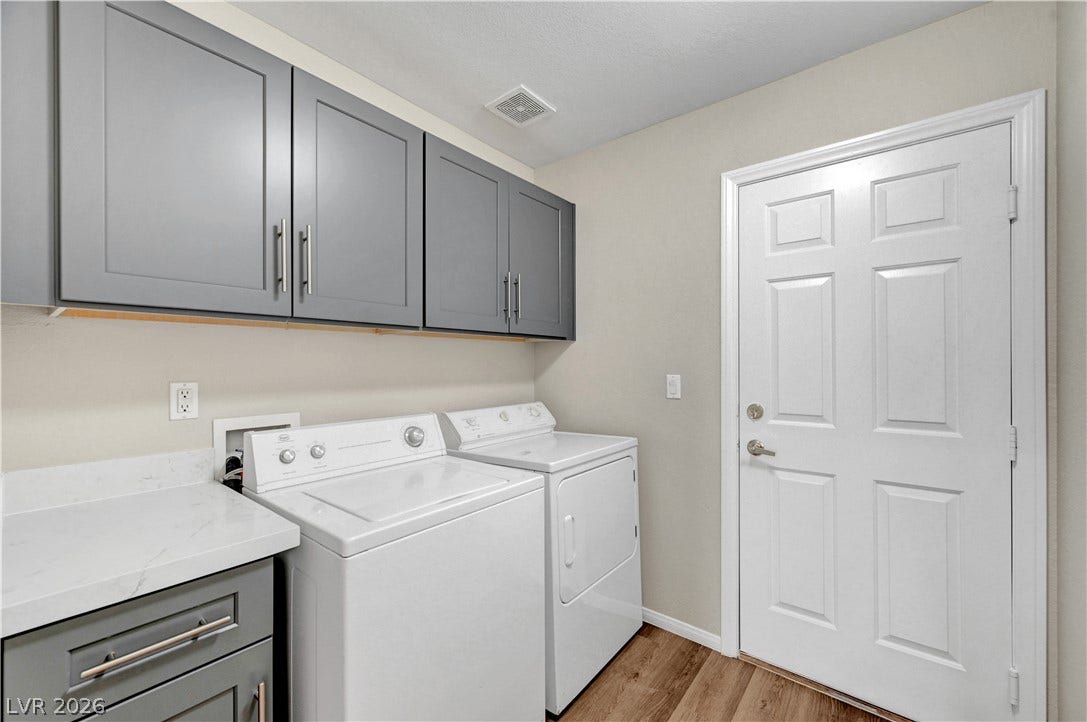 Ample cabinetry and stone-look countertops enhance this functional laundry space.