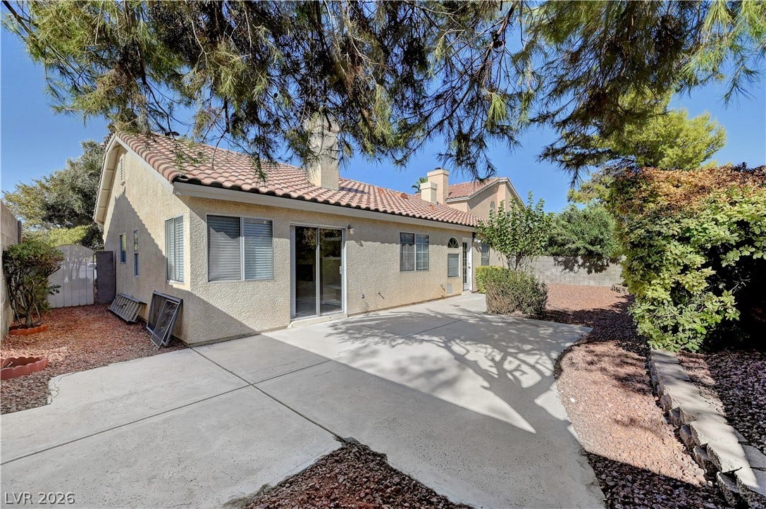 Mature trees shade a spacious concrete patio perfect for outdoor relaxation and entertaining.