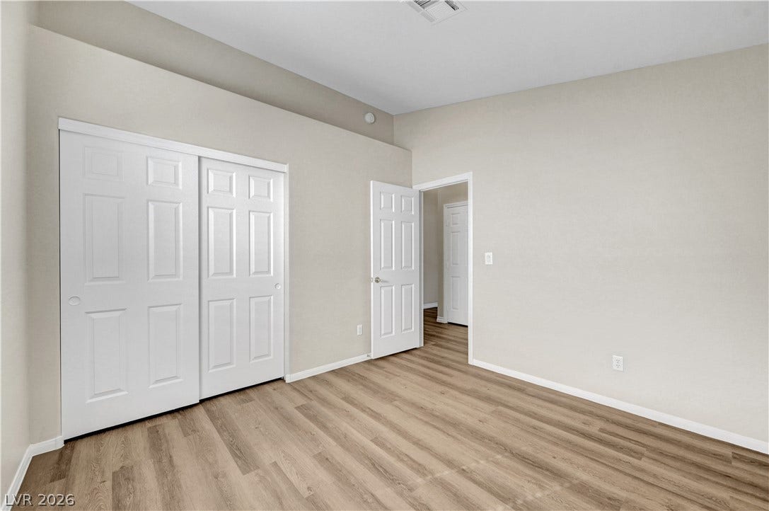 Gleaming wood-look floors pair with towering vaulted ceilings in this serene bedroom retreat.
