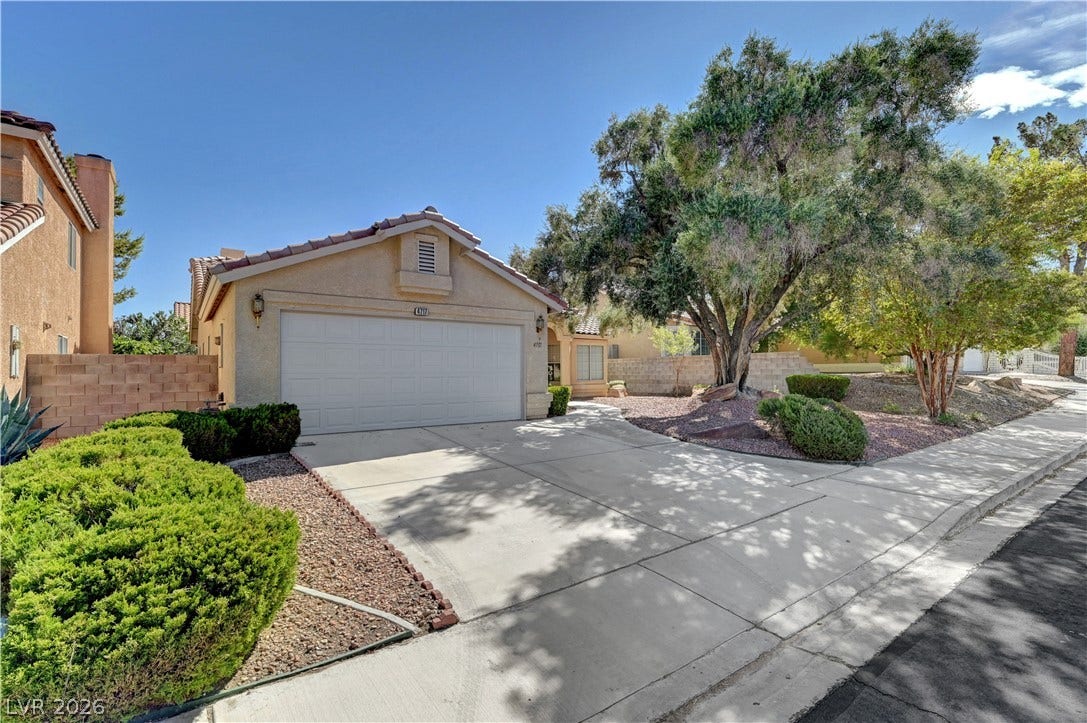 A spacious concrete driveway leads to the attached garage amidst neat desert landscaping.