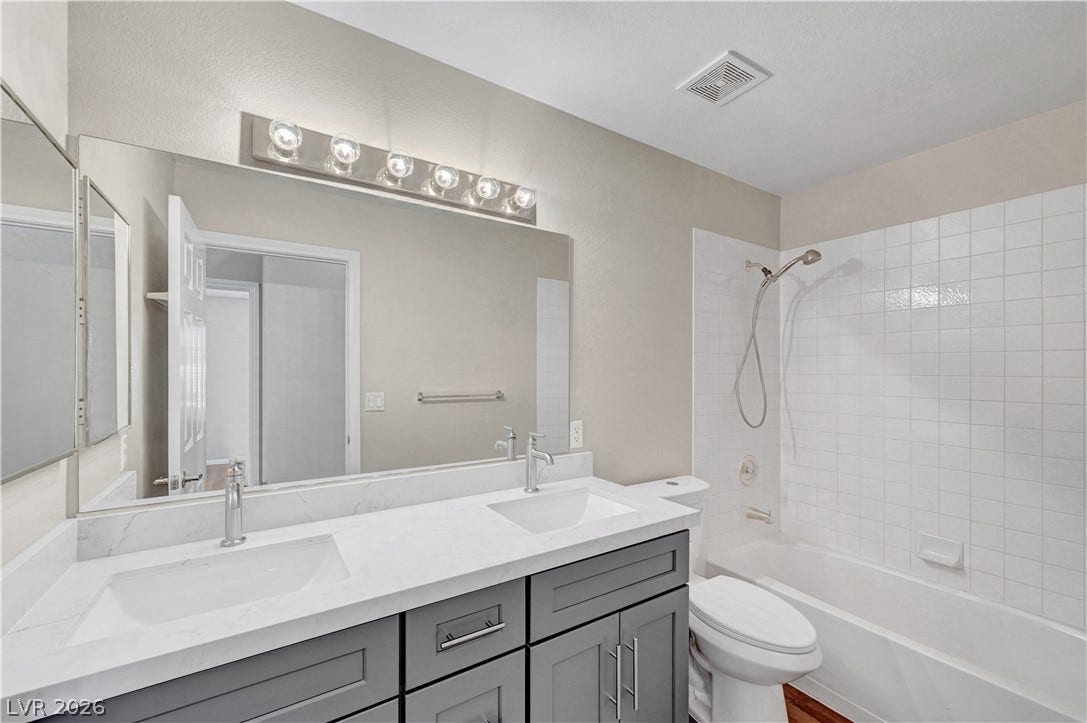 A classic tiled tub shower anchors this well-appointed bathroom alongside a modern double vanity.