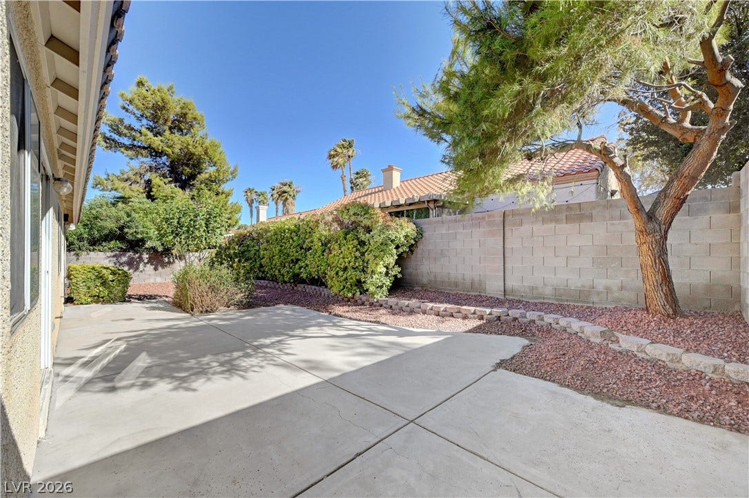 A spacious concrete patio offers a private outdoor retreat bordered by mature desert landscaping.