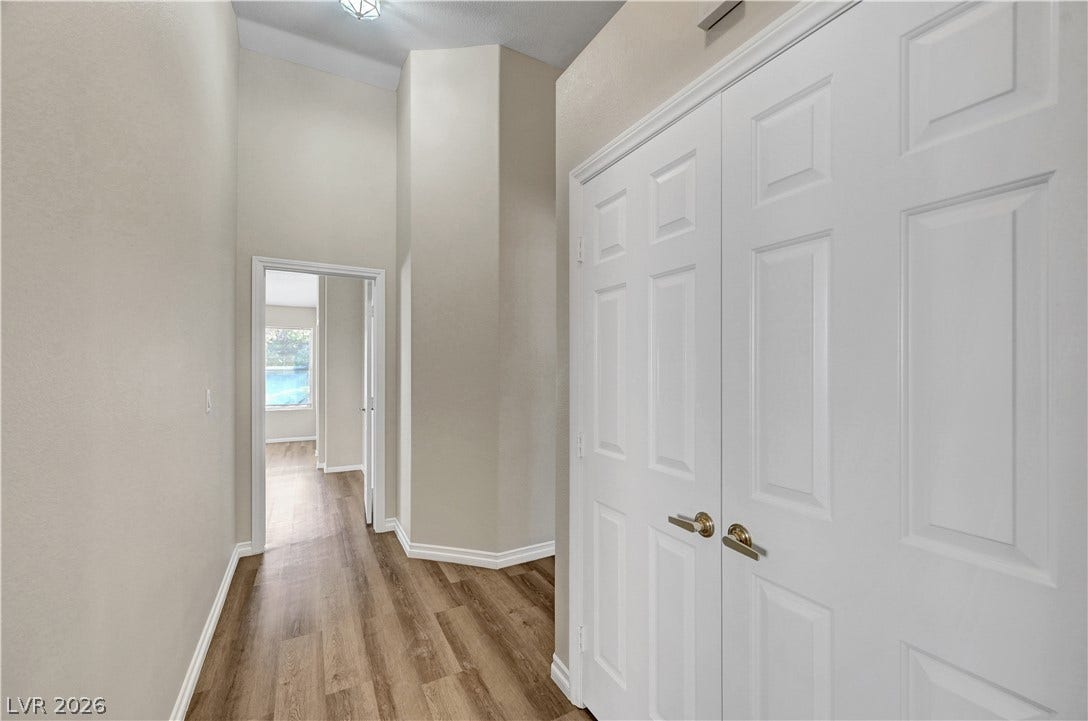 High ceilings and warm wood-look flooring define this welcoming hallway transition.
