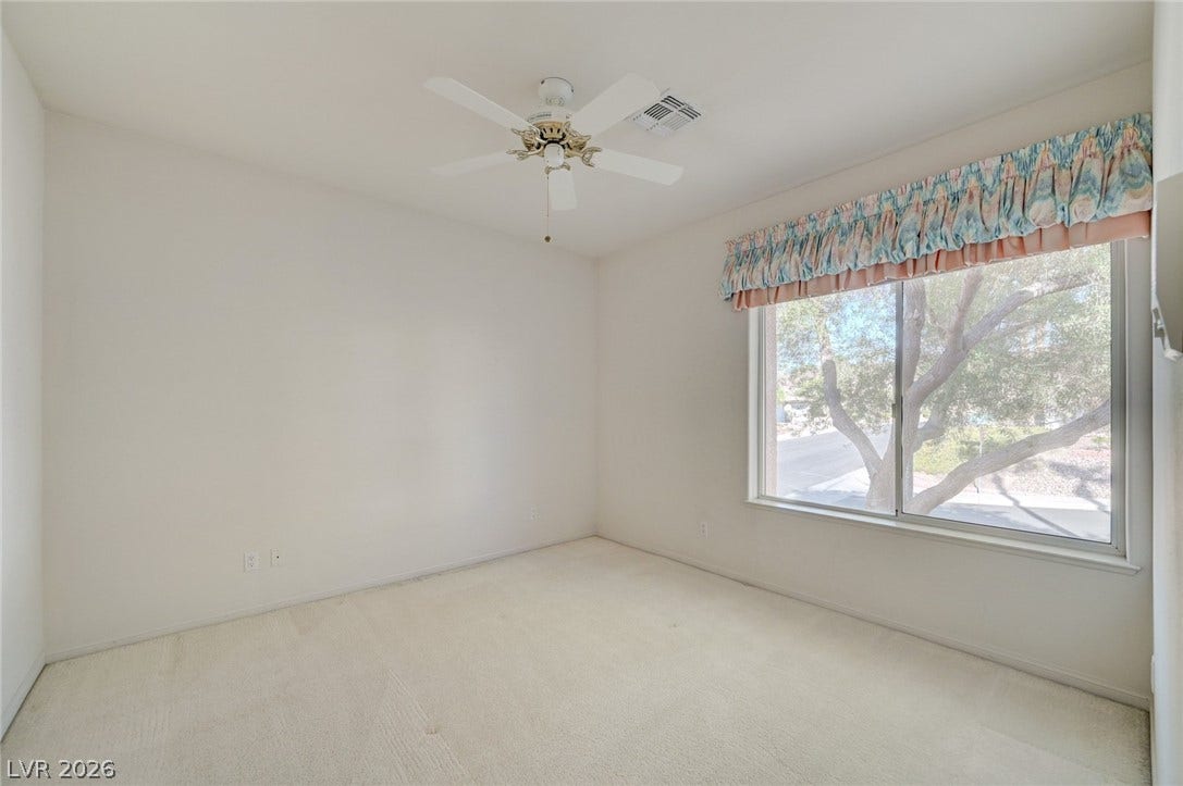 1112 Boletus Drive, Henderson, NV 89011 A wide window framing pleasant outdoor greenery anchors this carpeted bedroom.