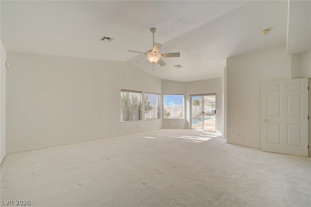 1112 Boletus Drive, Henderson, NV 89011 Sliding glass doors open from the carpeted living area to the backyard pool.