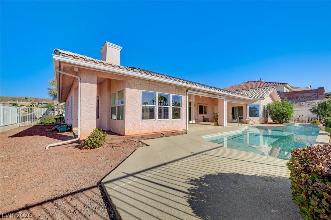 1112 Boletus Drive, Henderson, NV 89011 An inviting backyard swimming pool rests adjacent to a classic stucco exterior under clear skies.