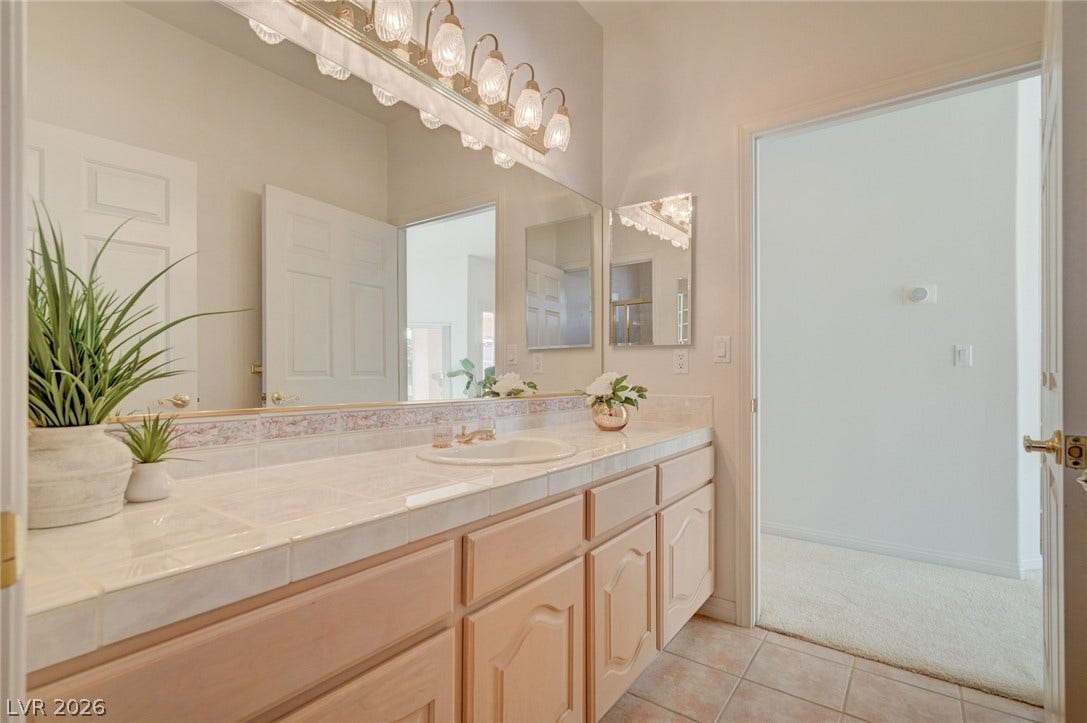 1112 Boletus Drive, Henderson, NV 89011 Tiled countertops and ample cabinetry define this functional vanity space with adjacent carpeted access.