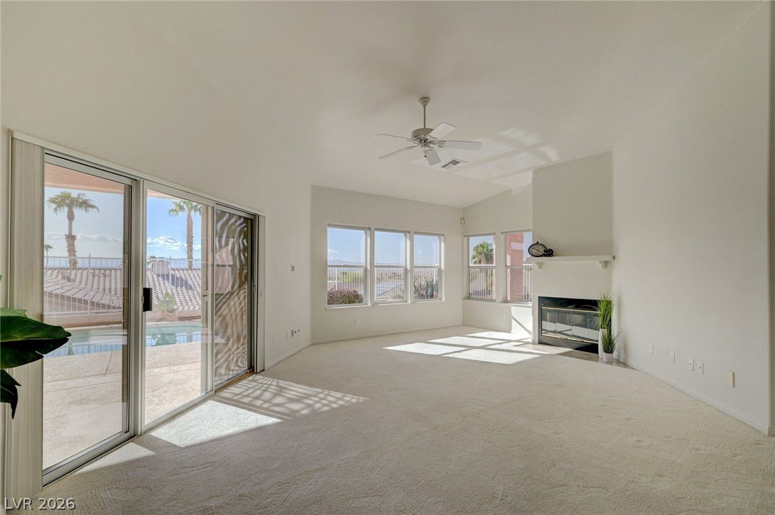 1112 Boletus Drive, Henderson, NV 89011 Plentiful natural light streams into a vaulted living space featuring a fireplace and sliding glass doors.