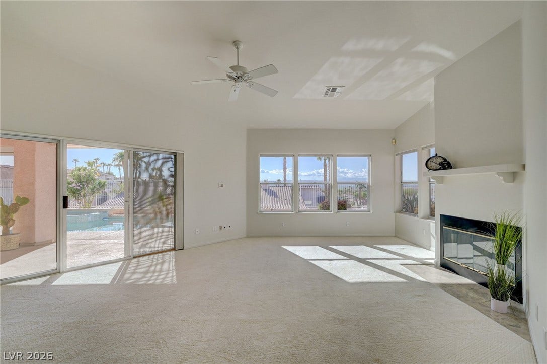 1112 Boletus Drive, Henderson, NV 89011 Sunlight streams across the carpeted living space featuring a fireplace and sliding glass doors.