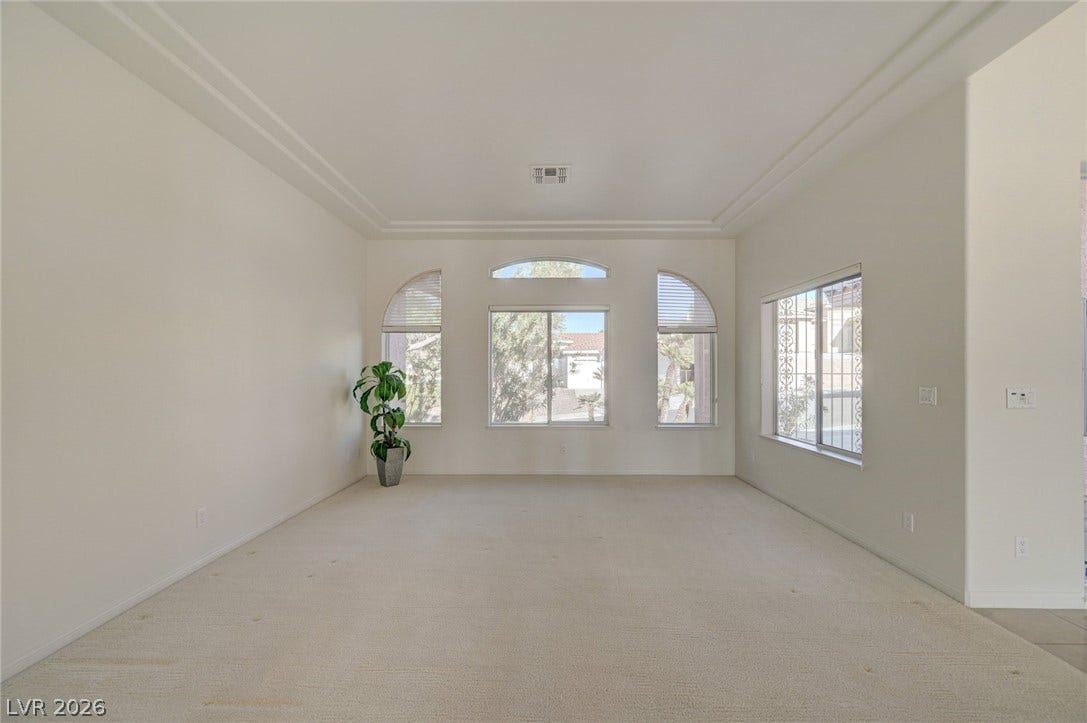1112 Boletus Drive, Henderson, NV 89011 Arched windows frame tranquil neighborhood views in this airy room with elegant stepped ceiling details.