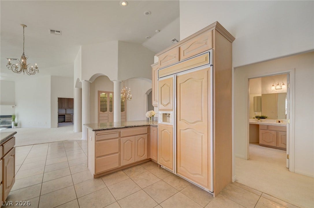 1112 Boletus Drive, Henderson, NV 89011 High ceilings and arched transitions define the open architectural layout of this tiled kitchen space.