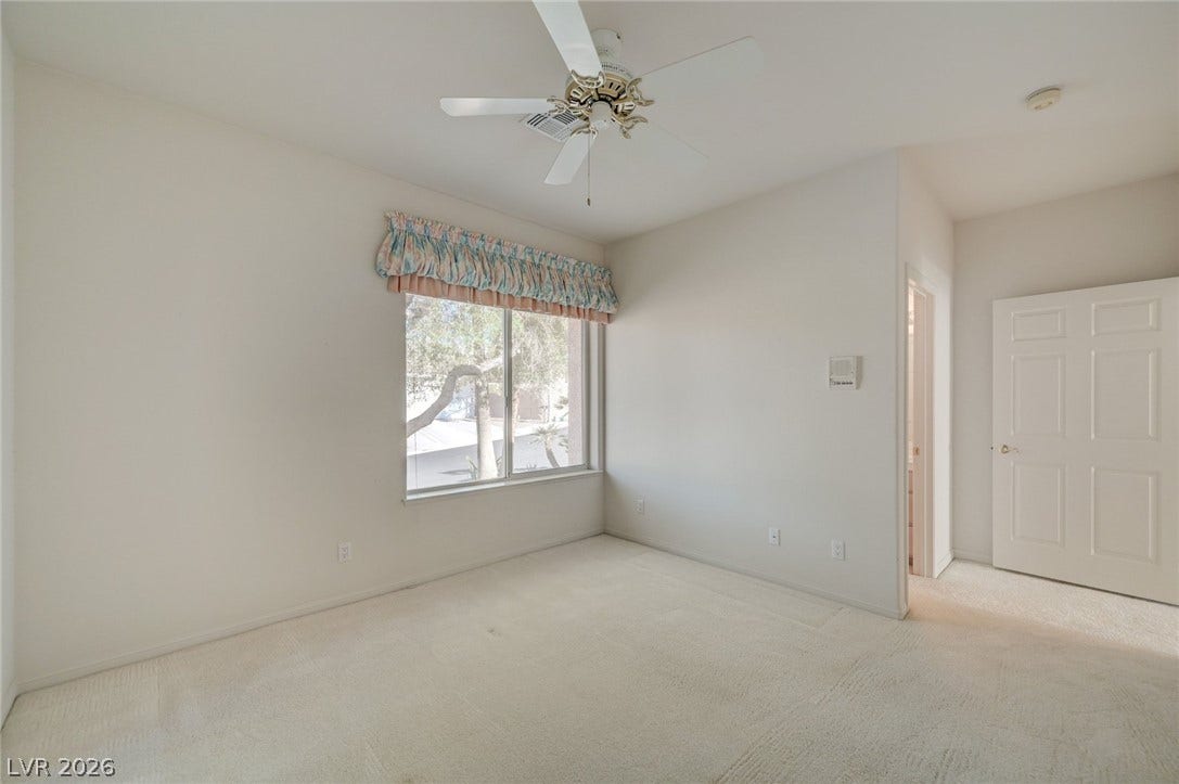 1112 Boletus Drive, Henderson, NV 89011 Plush carpeting anchors this peaceful bedroom featuring a large window that frames outdoor greenery.