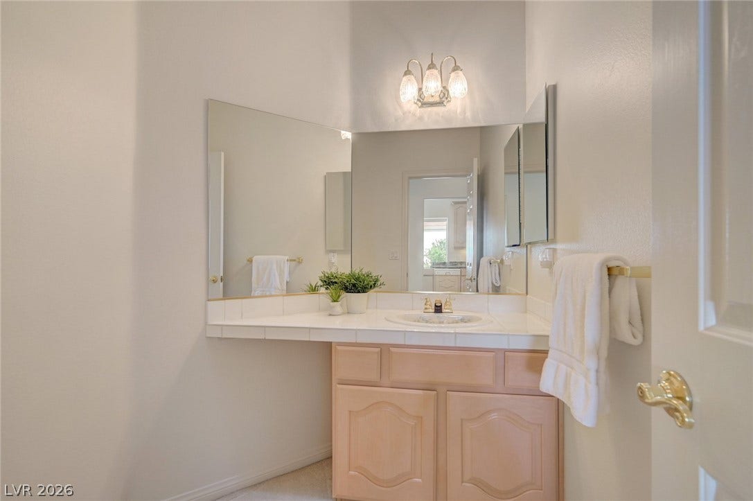 1112 Boletus Drive, Henderson, NV 89011 High ceilings and a tiled vanity with integrated mirrors define this bright bathroom space.