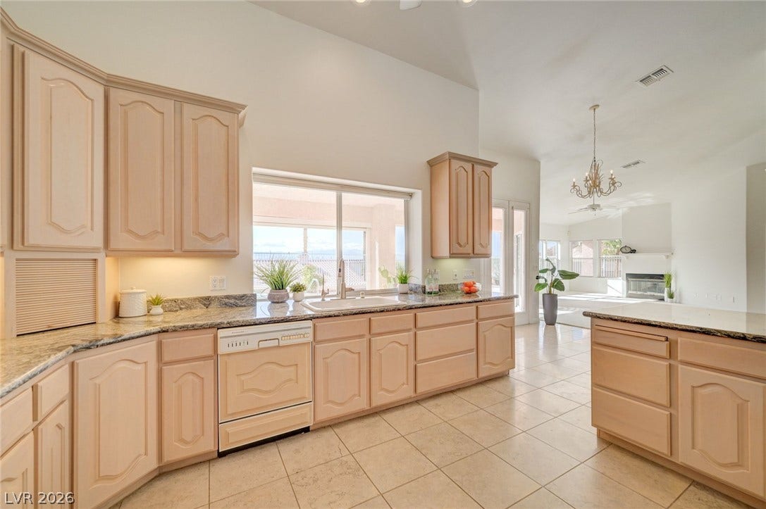 1112 Boletus Drive, Henderson, NV 89011 Vaulted ceilings soar over a sprawling tiled kitchen featuring stone counters and an adjacent dining area.