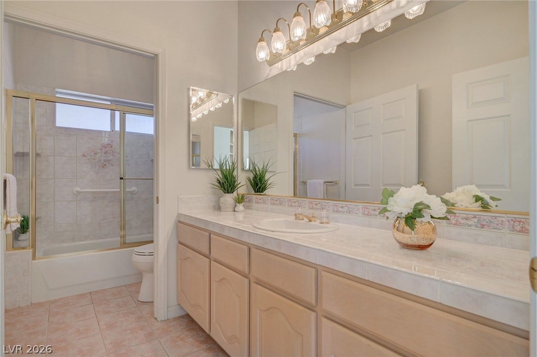 1112 Boletus Drive, Henderson, NV 89011 Tiled countertops and classic cabinetry define this functional, well-lit bathroom space.