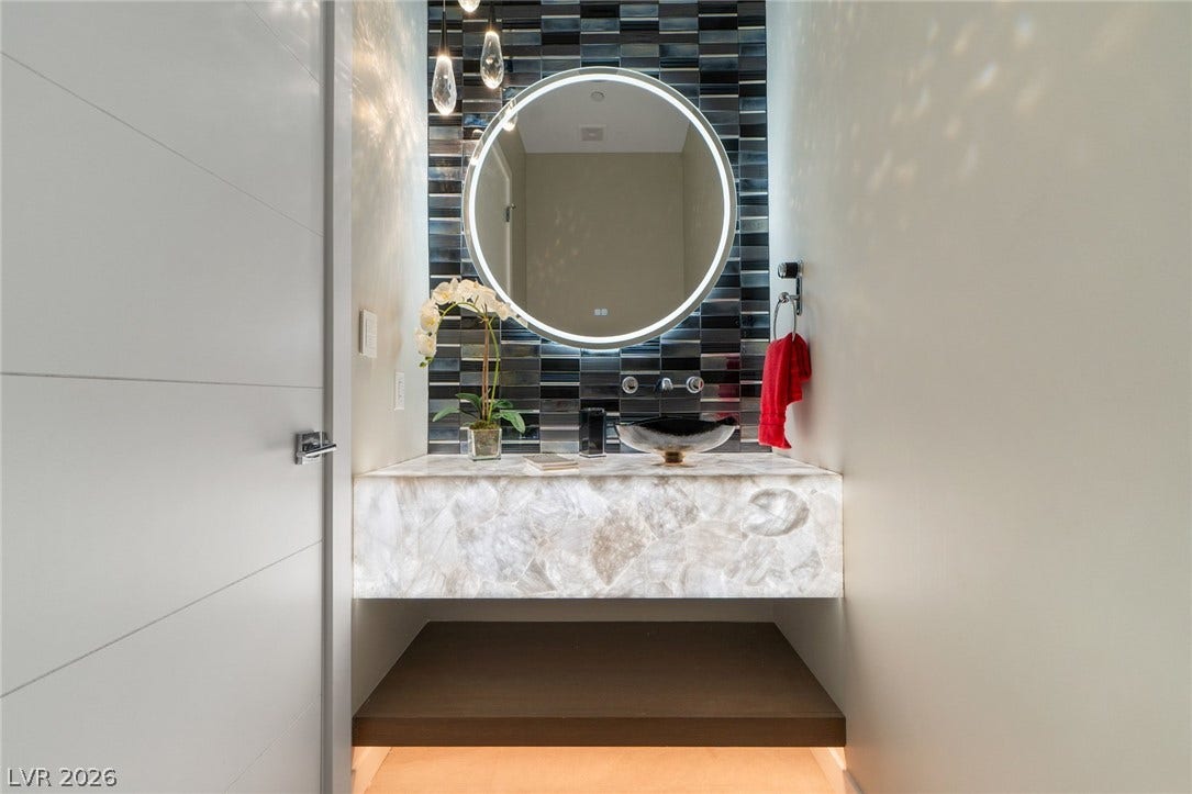 37 Reflection Shores Lane, Henderson, NV 89011 A floating backlit stone vanity and textured tile accent wall create a modern powder room.