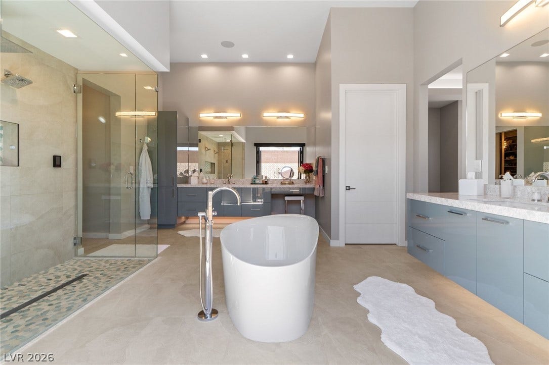 37 Reflection Shores Lane, Henderson, NV 89011 A freestanding tub and a glass-enclosed shower anchor this contemporary primary bathroom.