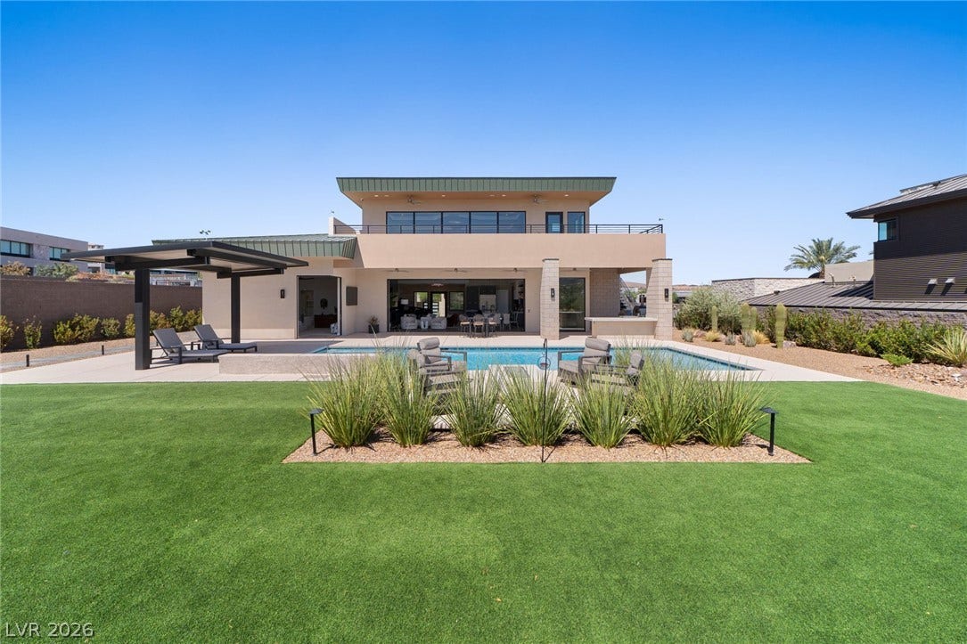 37 Reflection Shores Lane, Henderson, NV 89011 Modern architecture pairs with a pristine swimming pool and manicured lawn under clear desert skies.