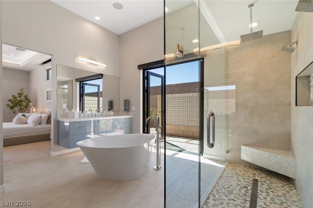 37 Reflection Shores Lane, Henderson, NV 89011 High ceilings and a glass-enclosed shower elevate this modern primary bath sanctuary.