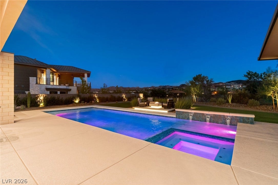 37 Reflection Shores Lane, Henderson, NV 89011 An inviting backyard oasis features a gleaming pool and spa under a clear twilight sky.
