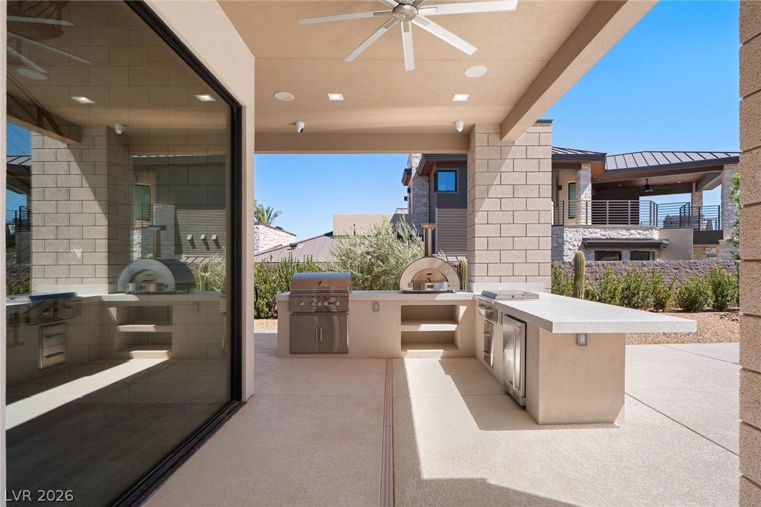 37 Reflection Shores Lane, Henderson, NV 89011 An outdoor kitchen sits under a covered patio next to expansive glass sliding doors.
