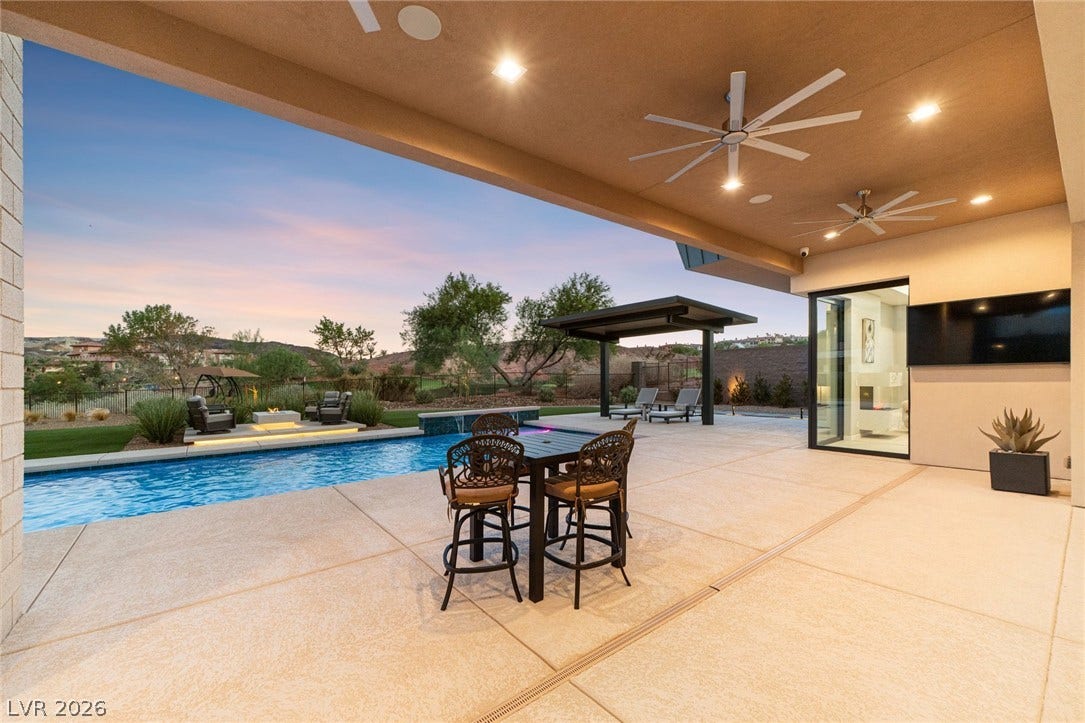 37 Reflection Shores Lane, Henderson, NV 89011 An expansive covered patio overlooks a sparkling in-ground pool and scenic natural landscape.
