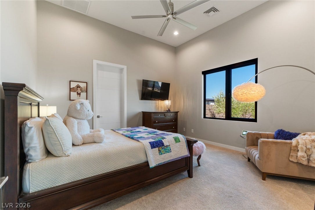 37 Reflection Shores Lane, Henderson, NV 89011 A spacious bedroom showcases carpeted flooring, high ceilings, and a large window looking outdoors.