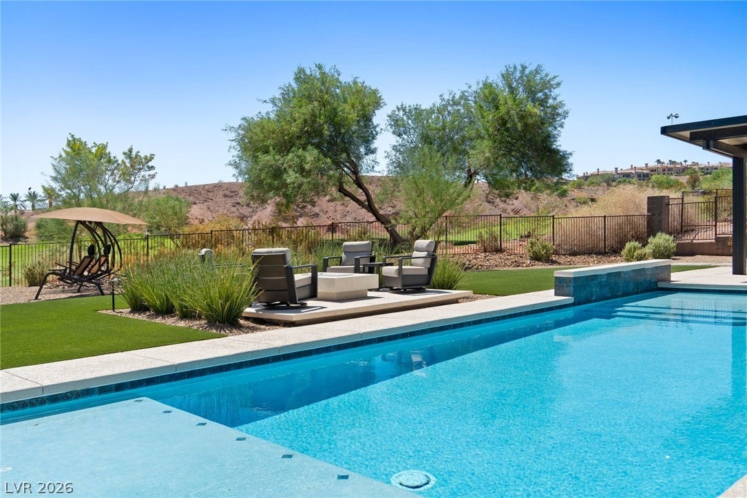 37 Reflection Shores Lane, Henderson, NV 89011 An inviting backyard oasis centers around a sparkling swimming pool bordered by manicured turf.