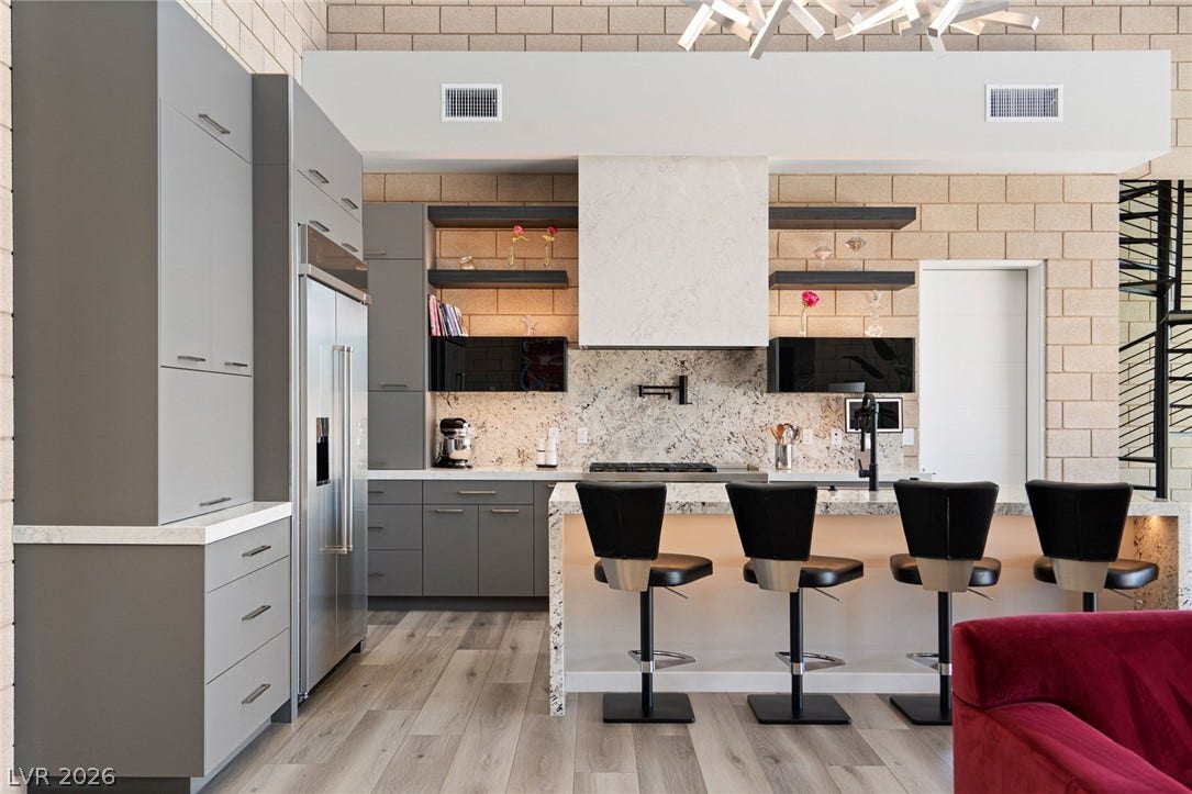 37 Reflection Shores Lane, Henderson, NV 89011 Industrial block walls and custom cabinetry define this modern kitchen featuring a stone-topped island.