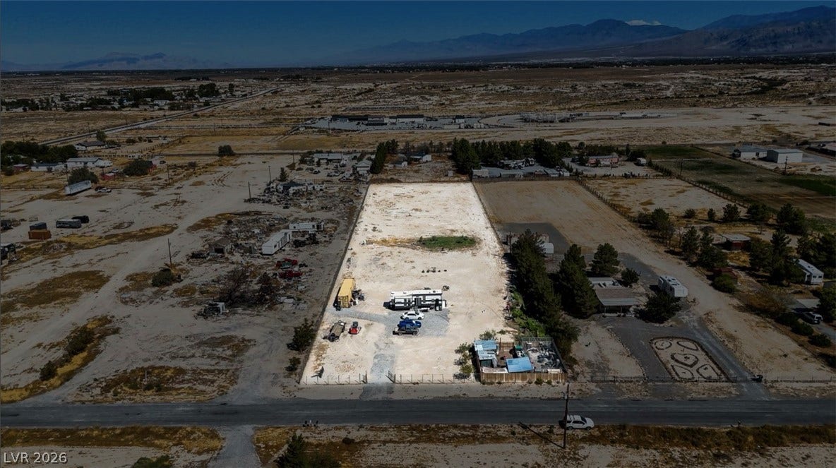 3160 Wall Street, Pahrump, NV 89061 A fenced desert parcel extends toward distant mountain ridges under clear blue skies.