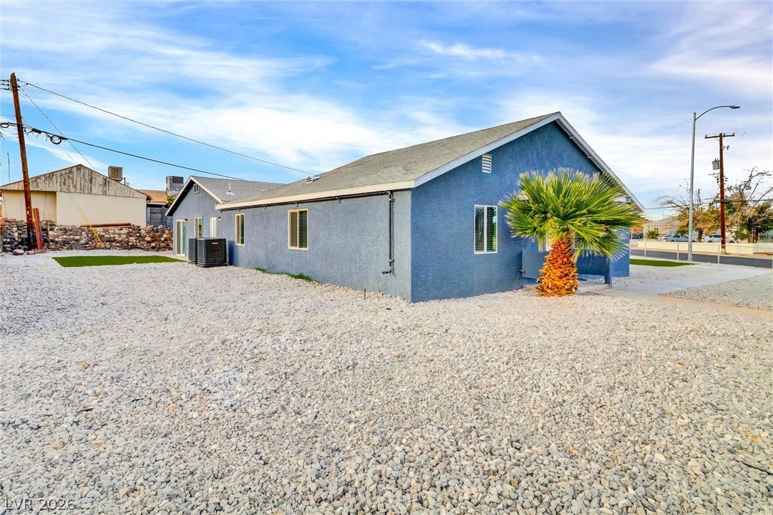 Gravel landscaping surrounds this modern stucco home nestled under a wide desert sky.