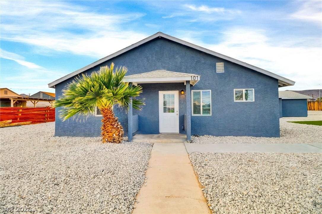 A concrete walkway leads to the welcoming front porch of this classic single-story stucco home.
