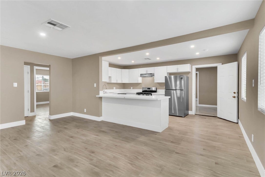 An open floor plan seamlessly connects the kitchen and main living areas over wood-look flooring.