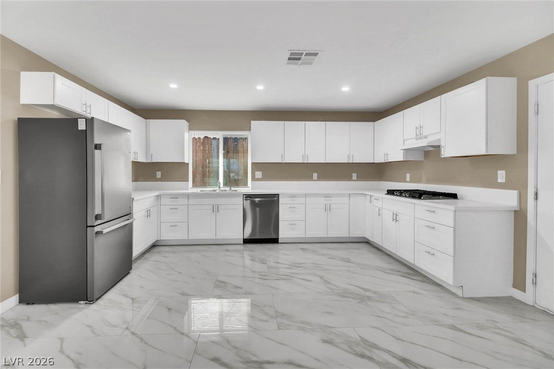 Gleaming stone-look tile floors anchor this modern culinary space lined with clean white cabinetry.