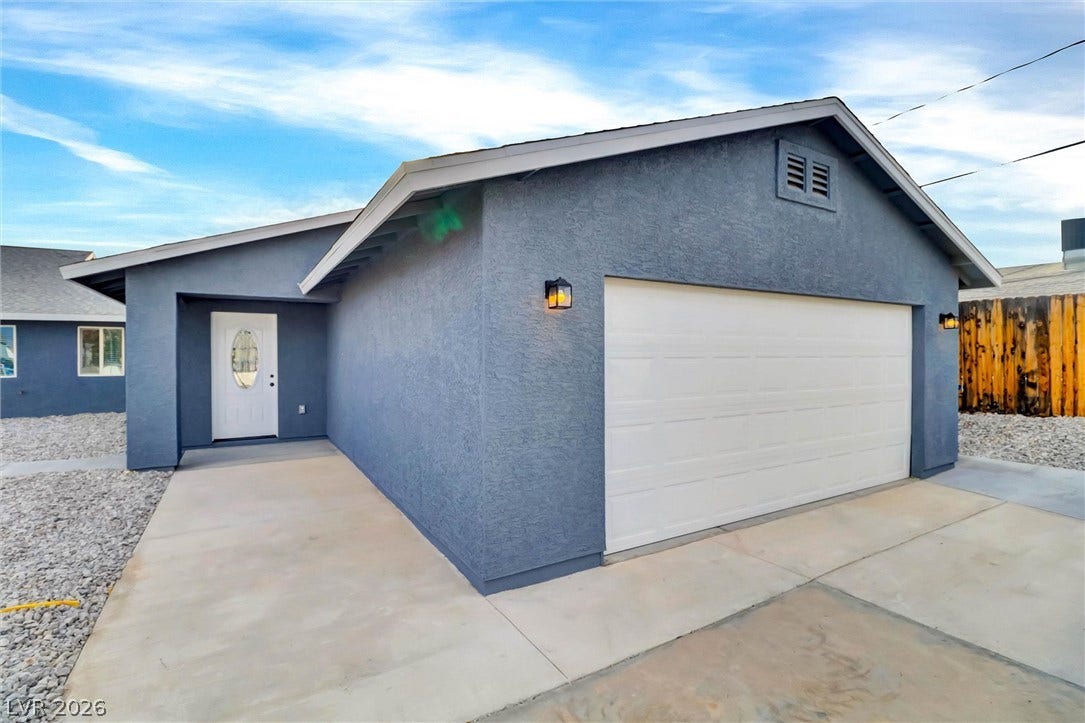 A spacious driveway and concrete path lead to a classic stucco exterior with attached garage.