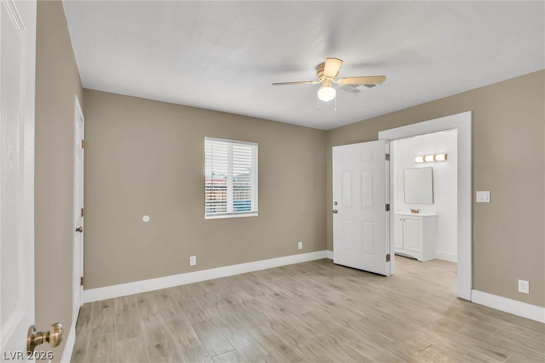 Smooth wood-look tile floors run through this bedroom with an attached bathroom.