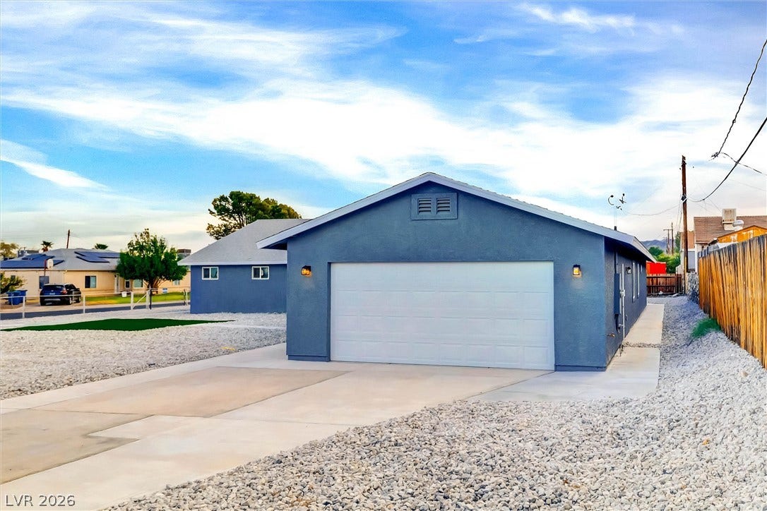 A spacious driveway leads directly to a secure two-car garage alongside a low-maintenance gravel yard.