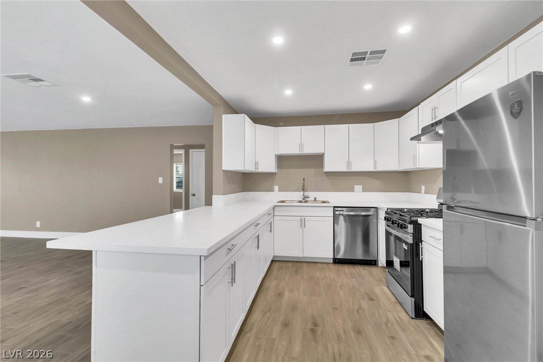 Gleaming stone counters and modern stainless steel appliances define this renovated open-concept kitchen.