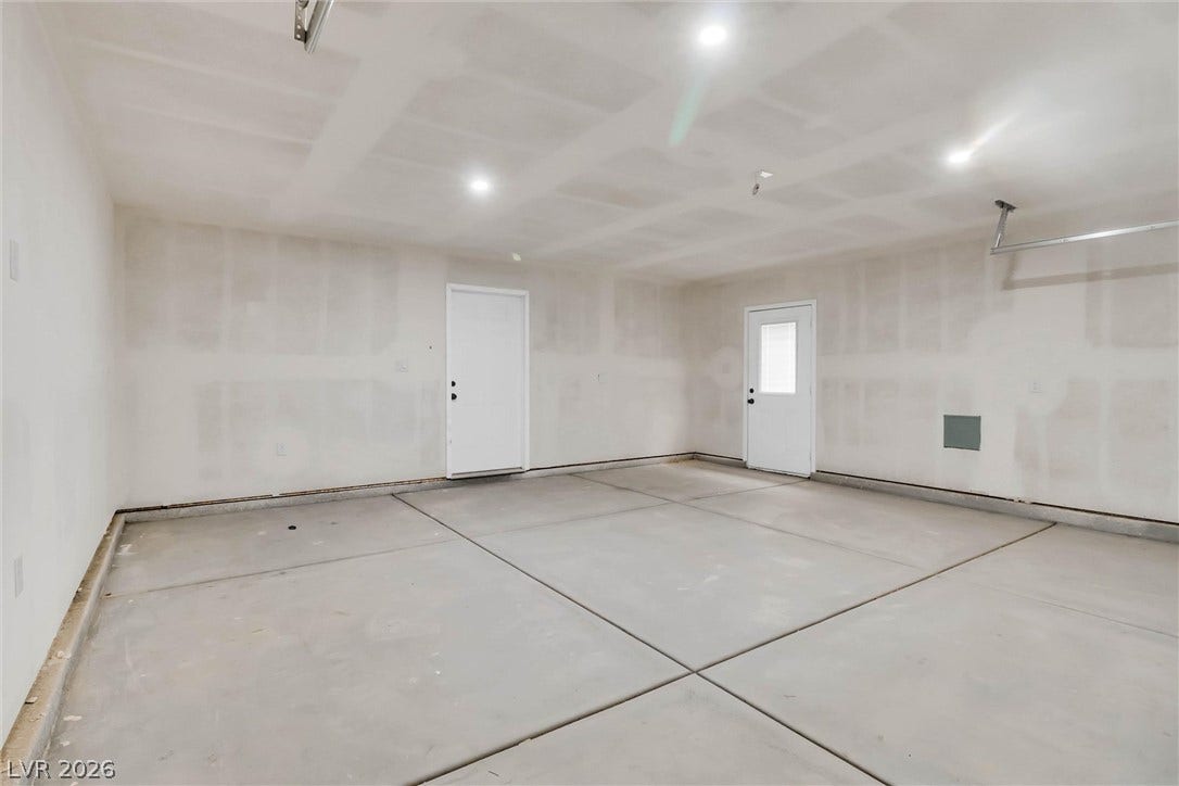 An expansive concrete floor and recessed lighting define this unfinished garage space.