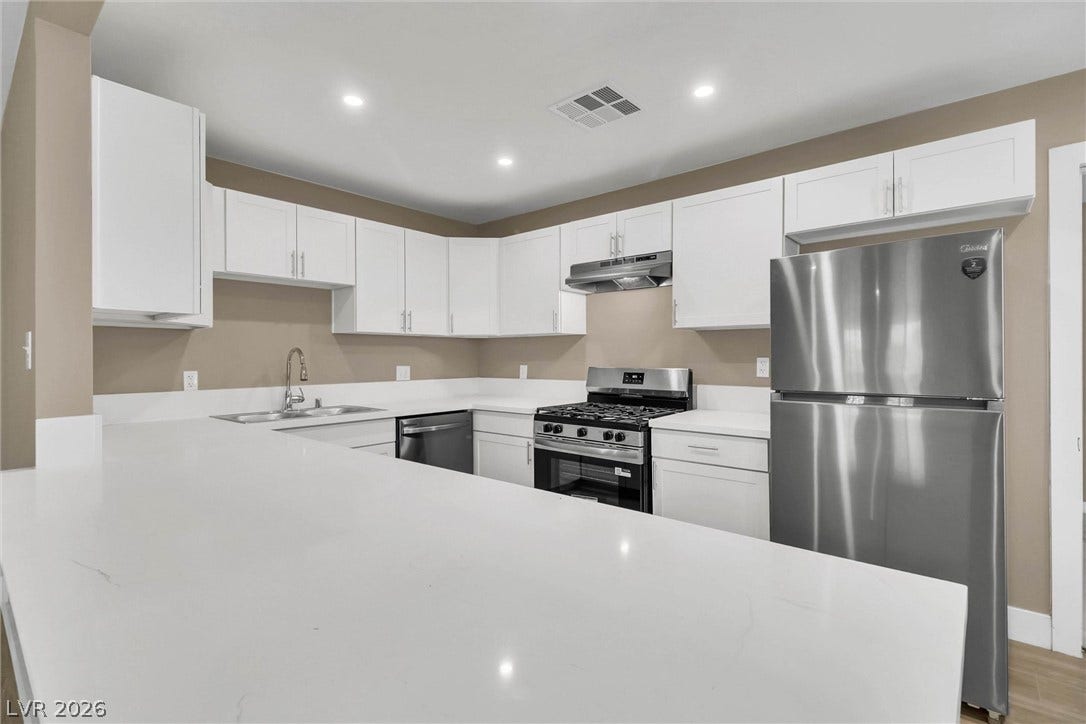 Polished stone countertops pair seamlessly with white cabinetry and modern stainless steel appliances.