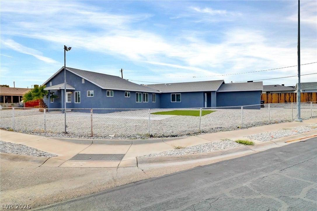 Chain-link fencing secures the low-maintenance gravel yard surrounding this single-story home.